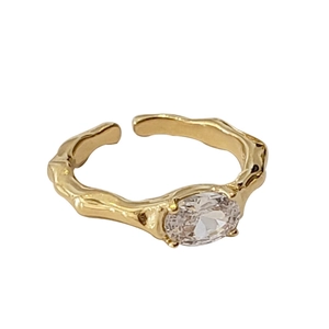 Adjustable gold irregular geometric ring with oval zircon on a white background