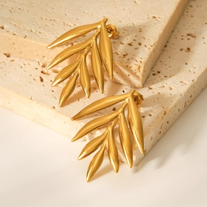 Minimalist 18K gold stainless steel leaf stud earrings on beige travertine stone