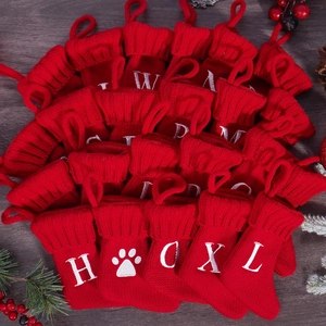 Close-up of red knitted Christmas mini stocking decorations with white letter embroidery
