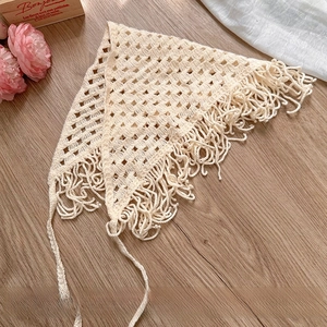 Detail of cream crochet knit bandana featuring hollow diamond pattern and tassels