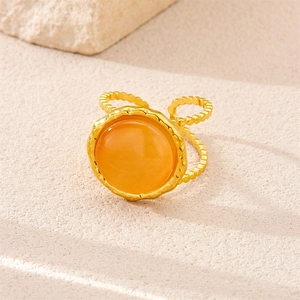 Macro shot of 18k gold plated stainless steel ring with orange gemstone and wave texture