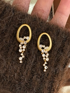 Détails de boucles d'oreilles ovales dorées avec zircons blancs et fini en métal brossé