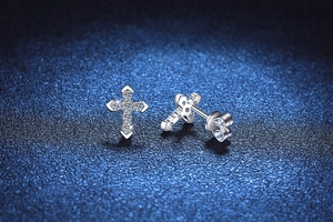 Macro shot of silver cross stud earrings with sparkling pavé moissanite on dark background