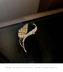 Détail de la broche épi de blé dorée avec des strass étincelants sur fond sombre