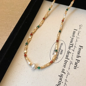 French style baroque pearl necklace with colorful beads and gold spacers on a beige tray