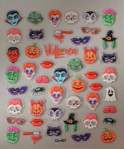 Macro shot of 3D Halloween nail stickers featuring embossed pumpkins and skulls