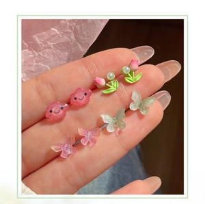 Detail of cute tulip, cloud, and butterfly stud earrings set with glitter resin finish