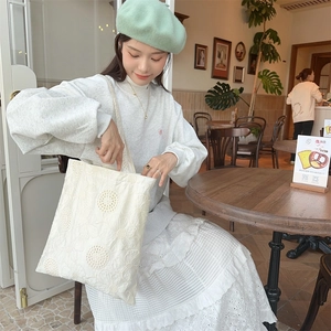 Detailed close-up of intricate sunflower embroidery and hollowed lace on the white tote bag