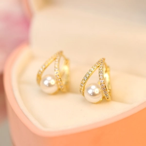 Macro shot of gold pearl earrings with zircon stones in a heart-shaped jewelry box