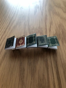 Detail of creative hair clip featuring five miniature vintage book charms on a metal base