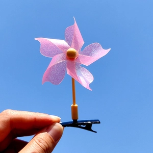 Détail d'une pince à cheveux moulin à vent rose pailleté avec centre jaune et clip noir