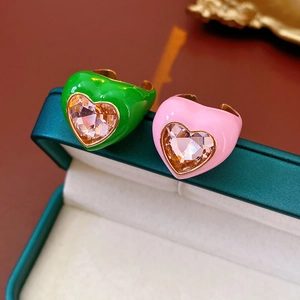 Close-up of heart-shaped enamel rings in green and pink with sparkling crystal inlay