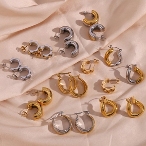 Fashionable C-shaped and layered hoop earrings in gold and silver on silk background