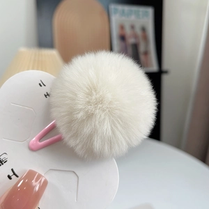 Detail of pink metal hair clip with white plush rabbit fur ball on a white display card