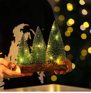 Macro view of three frosted mini Christmas trees with warm LED lights on a wooden base