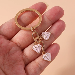 Detailed shot of a gold alloy keychain featuring three pink enamel diamond charms on a ring