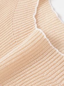 Detail of light beige mesh knit fabric featuring contrast white scalloped edge finish