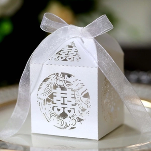 Detailed laser-cut Chinese wedding candy box in white paper with a silk ribbon bow