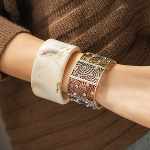 Detail of marble resin cuff and mixed-metal rhinestone bracelet on knit sleeve