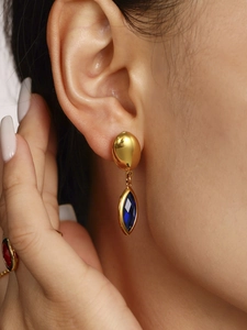 Détail de boucles d'oreilles en or 18K avec cristal bleu et bague pierre rouge