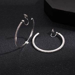 Detail of silver rhinestone clip-on earrings with spiral clasp on a black background