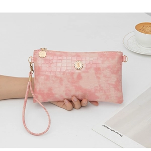 Detailed view of a pink crocodile pattern clutch bag with rhinestone hardware