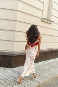 Back view of champagne satin maxi dress featuring red lace trim and long drawstring detail