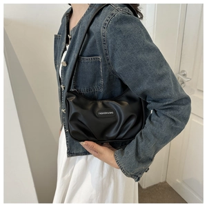 Sac baguette plissé noir porté par un mannequin avec une tenue décontractée en jean