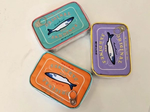 Three colorful sardine can storage pouches in blue, orange, and purple with metal pull rings