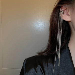 Silver fringe ear cuff with long metallic chains on model's ear, sleek minimalist style