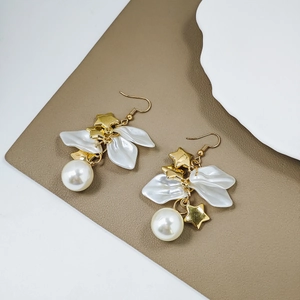 Detail of elegant gold earrings with white petals, pearls, and star charms set