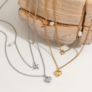 Double layer gold and silver heart star pearl necklaces draped on natural textured stone