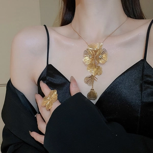 Detailed view of luxury gold floral necklace and ring set with rhinestones on model