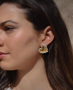 Gros plan de boucles d'oreilles cœur bicolores or et argent avec texture lave