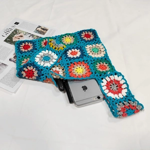 Close-up of handmade crochet bag featuring colorful floral patches and peacock blue weave