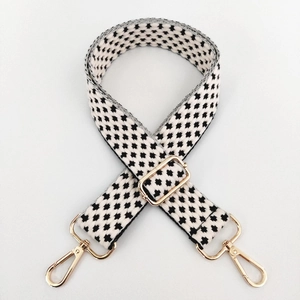 Detail of adjustable black and white houndstooth woven strap with gold metal swivel hooks