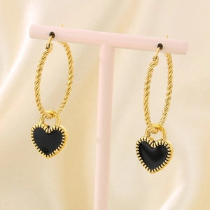 Détail de créoles torsadées dorées avec des pendentifs en forme de cœur en émail noir
