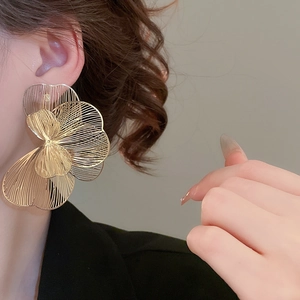 Vue détaillée de grandes boucles d'oreilles fleurs ajourées dorées au design métallique