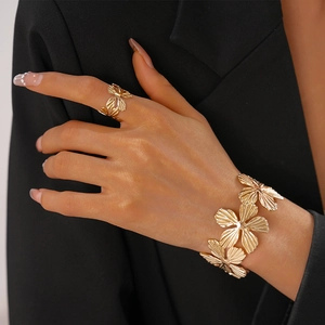 Detailed close-up of textured gold flower ring and bracelet set on a female model