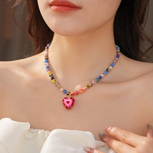 Close-up of a model wearing a colorful beaded necklace with a red heart pendant