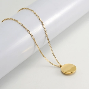 Detail of a golden round medal Evil Eye pendant necklace on a white column