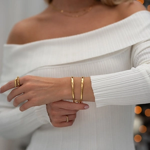 Minimalistisches goldenes Hohlarmband und Ring-Set getragen von Model für eleganten Stil
