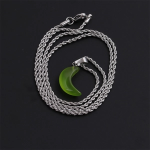 Detail of silver twisted rope chain with green crescent moon stone pendant over black background