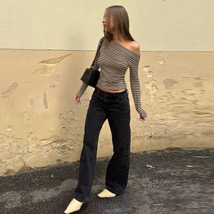 Détail du haut rayé gris à épaules dénudées avec un jean noir à jambes larges et bottines