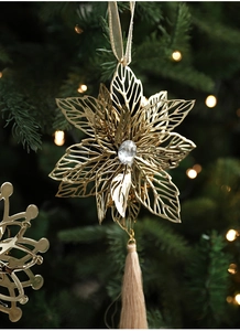 Close-up of golden hollow metal flower ornament with silk tassel on a Christmas tree