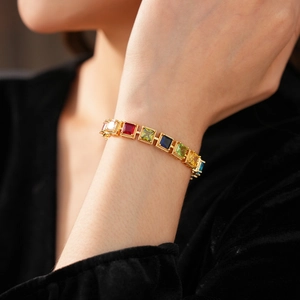 Détail d'un bracelet vintage doré serti de zircons carrés colorés au poignet féminin