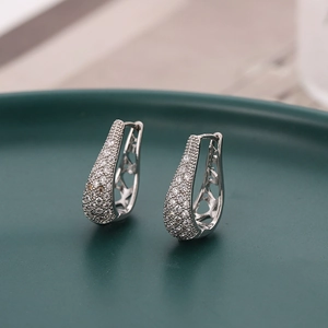 Elegant silver micro-pave teardrop earrings with hollow pattern on green ceramic tray