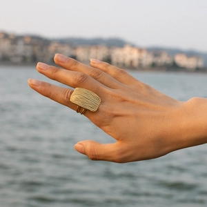 Detailed macro view of 18K gold stainless steel square ring with textured surface on finger