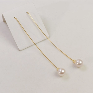Detail view of elegant white freshwater pearl drop earrings on a white display card