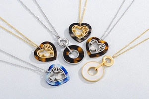 Flat lay of multiple stainless steel necklaces with round shell and heart love pendants